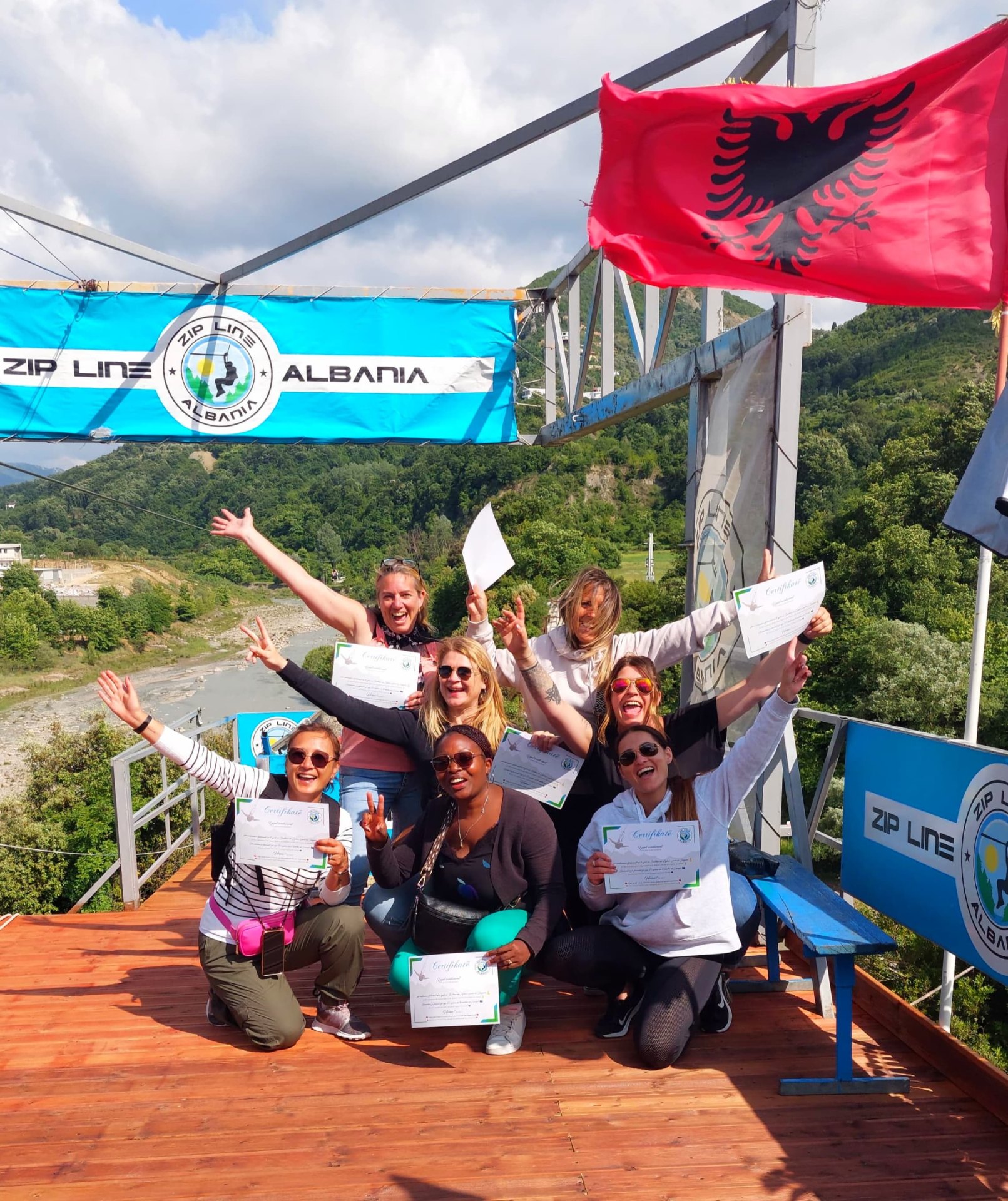 Group celebrating with certificates under Albanian flag